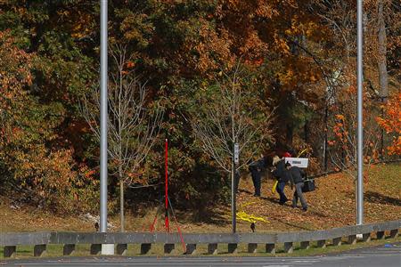 Investigators enter the woods behind the high school in Danvers, Massachusetts October 23, 2013. A 14-year-old student at a suburban high school in Boston, Massachusetts, was in custody Wednesday after police found the body of a teacher in the woods behind the school overnight, officials said. REUTERS/Brian Snyder