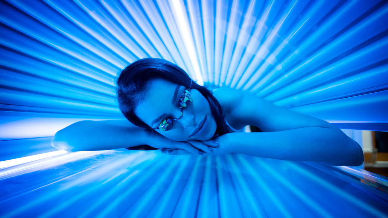 Attractive young woman smiling while tanning in solarium.