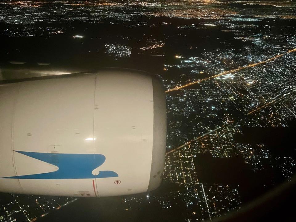 Looking out the window at night with city lights below and the engine.