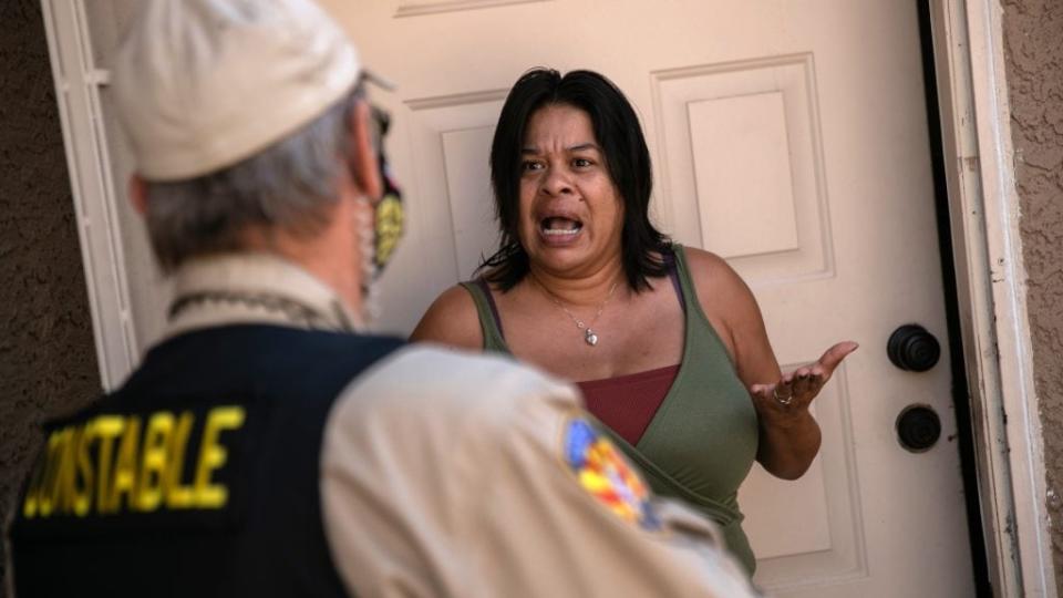 A tenant speaks with a Maricopa County constable who arrived with an eviction order in Phoenix. A federal judge has ruled that the national moratorium on evictions instituted by the Centers for Disease Control and Prevention is unconstitutional. (Photo by John Moore/Getty Images)