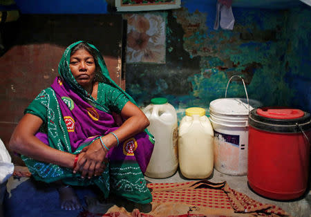 Sushila Devi, whose husband and son died after a brawl with neighbours over water in March, sits next to water containers inside her house in New Delhi, India, June 27, 2018. REUTERS/Adnan Abidi