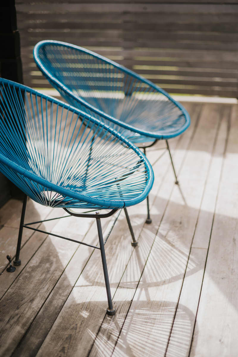 Blue deck chairs on a patio in the sun.