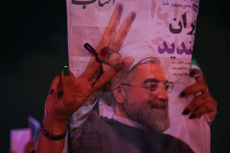 A supporter of Iranian president Hassan Rouhani holds his poster as she celebrates his victory in the presidential election, in Tehran, Iran, May 20, 2017. TIMA via REUTERS