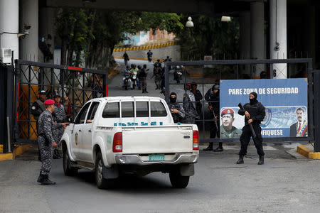 Members of the Bolivarian National Intelligence Service (SEBIN) stand guard next to a banner with the images of Venezuela's President Nicolas Maduro and Venezuela's late President Hugo Chavez, outside a detention center, where a riot occurred, according to relatives, in Caracas, Venezuela May 16, 2018. REUTERS/Carlos Garcia Rawlins