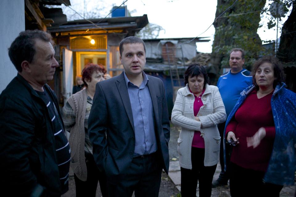 In this photo taken on Wednesday, Nov. 27, 2013, Igor Zarytovsky, center, and his father Vladimir, left, gather with their neighbors in the yard of the railroad house in the village of Vesyoloye outside Sochi, Russia. As the Winter Games are getting closer, many Sochi residents are complaining that their living conditions only got worse and that authorities are deaf to their grievances. (AP Photo/Alexander Zemlianichenko)