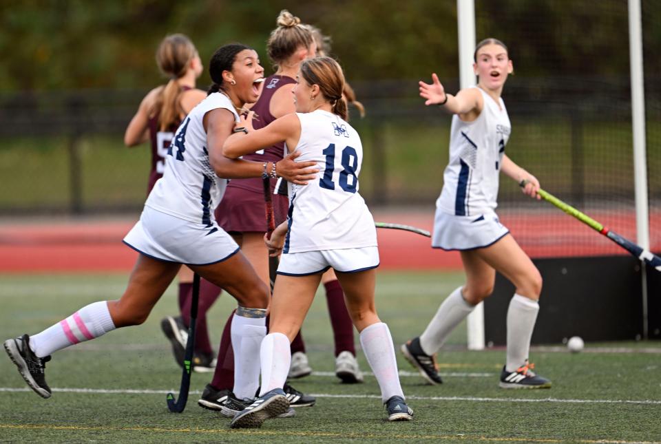 In this Oct. 6, 2023 photo, Monomoy players Savannah Brown (left) and Sam Clarke (right) turn to celebrate with Sage Harrison (18) after she scored the winning goal against Falmouth with seconds left in the match.