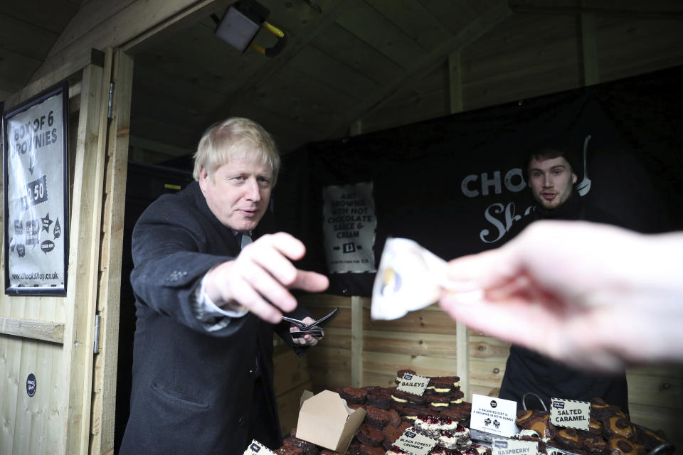 Boris Johnson borrows some cash to pay for chocolate at a Christmas market in Salisbury.