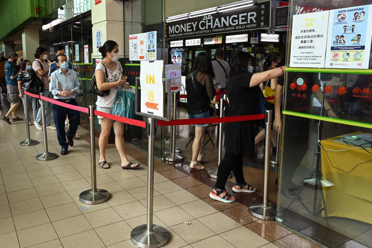 People queue as they wait to use a check-in service to enter a shopping centre in Chinatown in Singapore. 