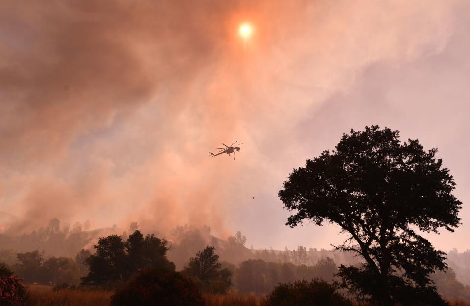 <p>A water dropping helicopter works the scene as the Pawnee fire jumps across highway 20 near Clearlake Oaks, Calif. on July 1, 2018. (Photo: Josh Edelson/AFP/Getty Images) </p>