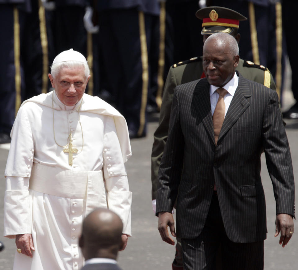 CAPTION CORRECTS AGE - FILE - Angolan President Jose Eduardo dos Santos, right, walks with Pope Benedict XVI during the guard of honor ceremony at the Luanda International Airport in Angola, Friday March 20, 2009. Former Angolan president Jose Eduardo dos Santos has died in a clinic in Barcelona, Spain after an illness, the Angolan government said. He was 79 years old and died following a long illness, the government said Friday, July 8, 2022 in an announcement on its Facebook page. (AP Photo/Themba Hadebe, File)