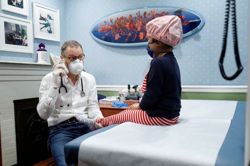 Dr Greg Gulbransen uses a girls shoe as a phone to cheer her up at his pediatric practice in Oyster Bay