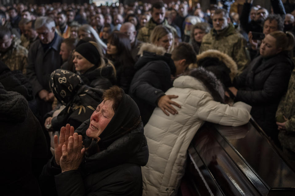 ARCHIVO - Parientes y amigos asisten al funeral de cuatro militares ucranianos fallecidos durante un ataque aéreo a una base militar en Yavoriv, en una iglesia de Leópolis, Ucrania, el martes 15 de marzo de 2022. Como hito, el primer aniversario de la invasión rusa en Ucrania es tan sombrío como exasperante. Es un año repleto de muerte, destrucción, pérdida y daños que se sienten mucho más allá de las fronteras de Rusia y Ucrania. (AP Foto/Bernat Armangué, Archivo)