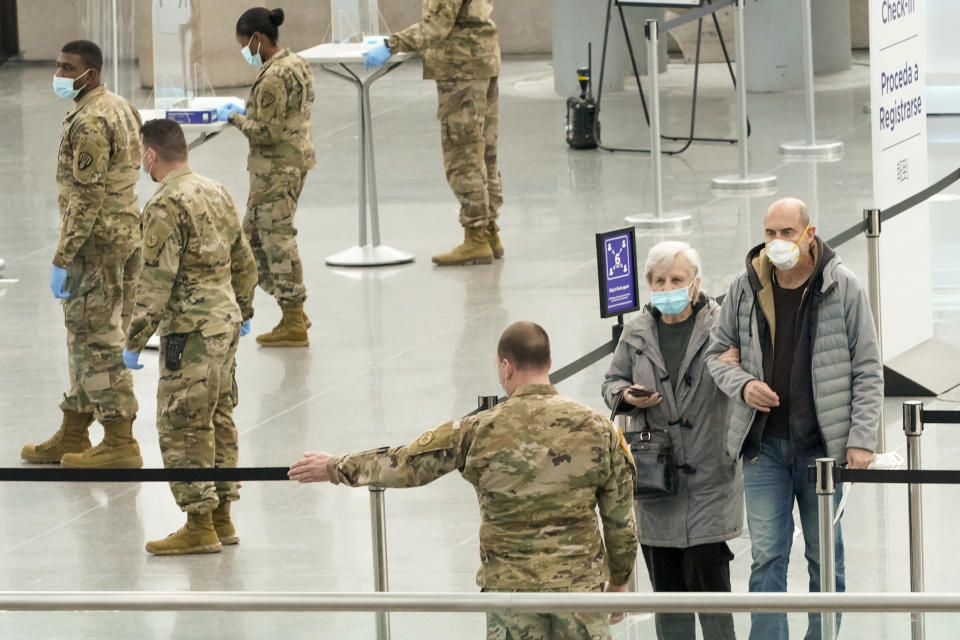 A member of the National Guard directs seniors as they arrive to be vaccinated against COVID-19 at a New York State vaccination site in the Jacob K. Javits Convention Center, Wednesday, Jan. 13, 2021, in New York. New York state expanded COVID-19 vaccine distribution Tuesday to people 65 and over, increasing access to an already short supply of doses being distributed. (AP Photo/Mary Altaffer)