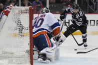 New Jersey Devils' Nico Hischier, right, tries to make a shot on New York Islanders goaltender Semyon Varlamov during the second period of an NHL hockey game in Newark, N.J., Monday, April 15, 2024. (AP Photo/Seth Wenig)