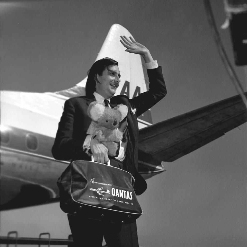 Barry Humphries, holding a toy koala bear and Qantas travel bag, in 1965 - Getty