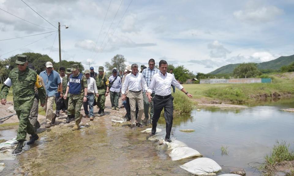 President Enrique Peña Nieto, right, inspects affected areas in Pueblo state. He was booed by students in his home state of Mexico.