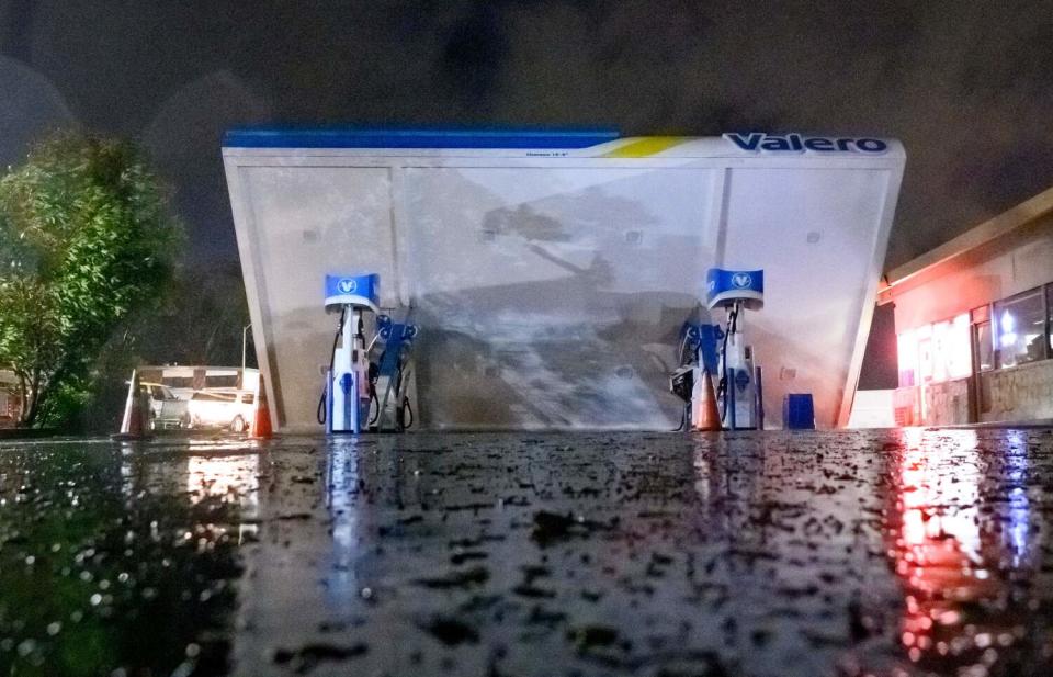 The roof over gas pumps at a gas station is blown over.