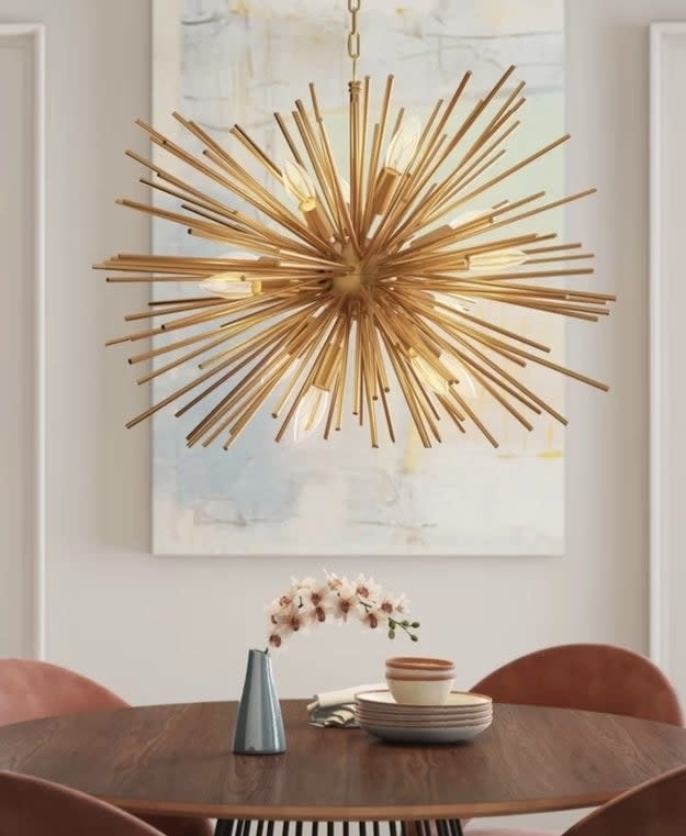 A spiky spherical chandelier hanging above a dining table with dishes and a vase with flowers