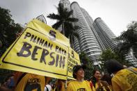 FILE - In this Nov. 19, 2016, file photo, activists from the Coalition for Clean and Fair Elections (BERSIH) show a placard reading "Clean Election BERSIH" in front of the Petronas Towers during a rally against corruption in Kuala Lumpur, Malaysia. A survey by the anti-graft group Transparency International shows that bribery and other forms of corruption are hindering poverty alleviation and hurting public health by channeling resources away from those who need them. The survey, released Tuesday, March 7, 2017, estimated that more than 900 million people in the region had paid bribes in the past year to obtain basic public services like schooling and health care. (AP Photo/Vincent Thian, File)