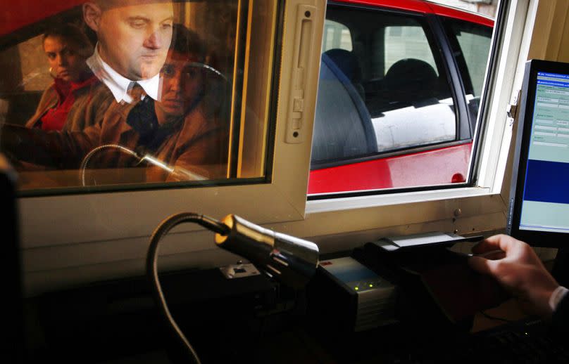 a Bulgarian border policeman, reflected in glass, checks documents of people traveling by car, at the Kapitan Andreevo border, January 2011