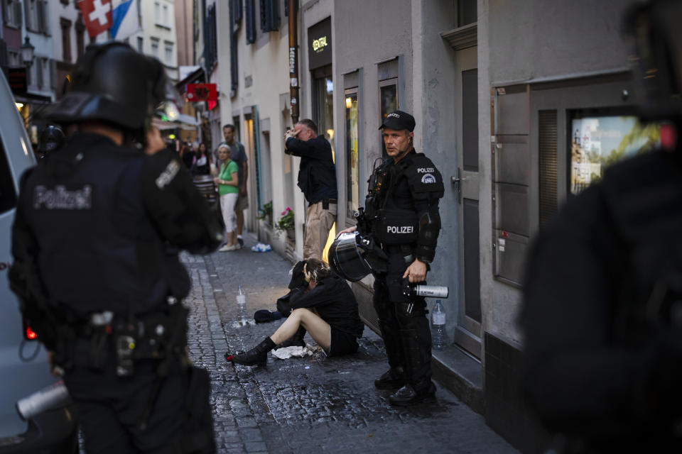 An injured young woman, center, is held by police officers next to an injured police officer in plain clothes, center back, after the police used pepper spray and rubber bullets against protesters during a demonstration against the World Economic Forum (WEF) in Zurich, Switzerland, Friday, May 20, 2022. The World Economic Forum Annual Meeting will take place from May 22-26, in Davos. (Michael Buholzer/Keystone via AP)
