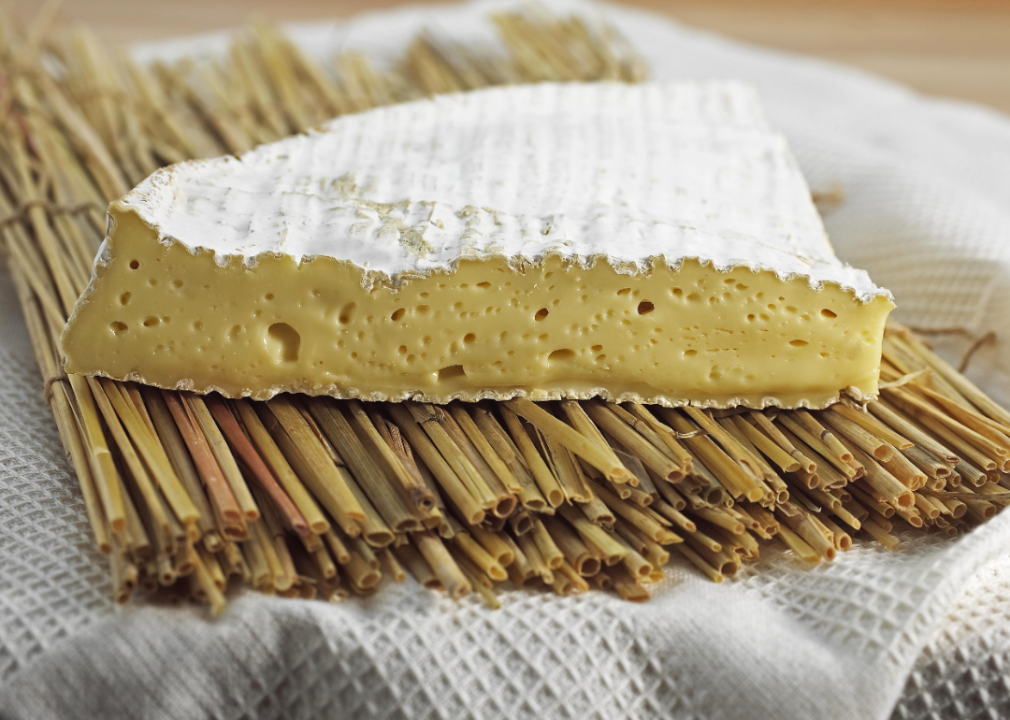 A slice of Brie on a bed of bundled straw.