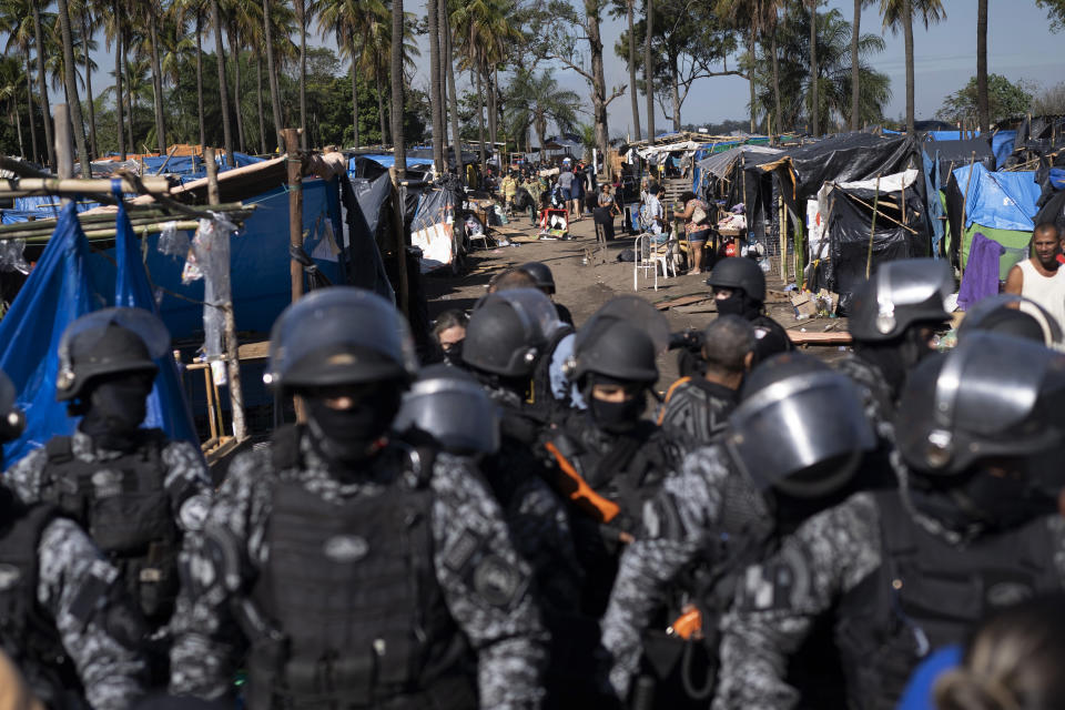 Security forces stand guard as they evict people from land designated for a Petrobras refinery, at a settlement coined the "First of May Refugee Camp," referring to the date people moved here and set up tents and shacks to live in during the new coronavirus pandemic in Itaguai, Rio de Janeiro state, Brazil, Thursday, July 1, 2021. (AP Photo/Silvia Izquierdo)