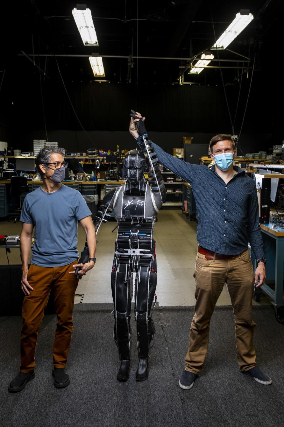 Two men holding hands with a humanoid robot