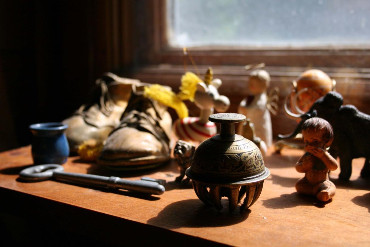 Closeup of several of vintage knick-knacks dusty old shelf, light coming through window onto the items, window and darken wall in the background