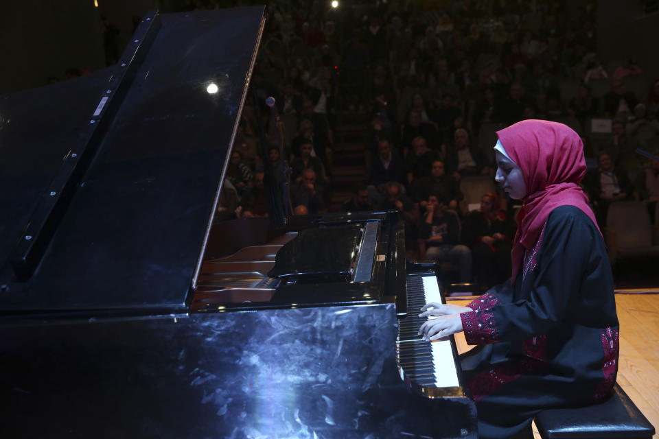 Palestinian pianist Yara Thabit pianist plays the piano during a concert to mark the debut of Gaza's only grand piano after it was rescued from conflict, at a theater nestled in the Palestinian Red Crescent Society's building in Gaza City, Sunday, Nov. 25, 2018. The only grand piano in the Gaza Strip is debuting to the public for the first time in over a decade after its restoration. (AP Photo/Adel Hana)