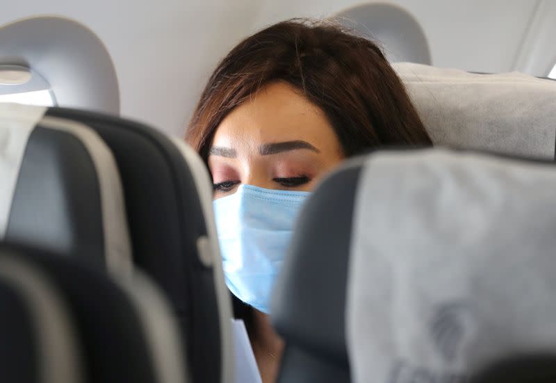 FILE PHOTO: A traveller wears a protective face mask on a plane following an outbreak of the coronavirus disease (COVID-19) in Cairo