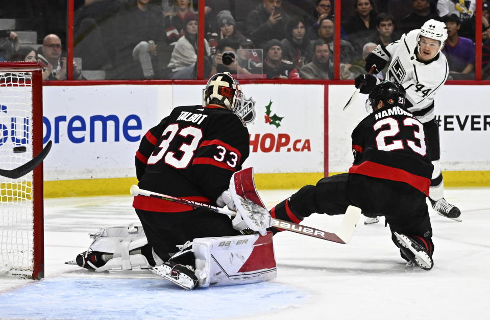 Los Angeles Kings defenseman Mikey Anderson scores on Ottawa Senators goaltender Cam Talbot (33) as defenseman Travis Hamonic (23) attempts to block a shot, during the first period of an NHL hockey game, Tuesday, Dec. 6, 2022, in Ottawa, Ontario. (Justin Tang/The Canadian Press via AP)