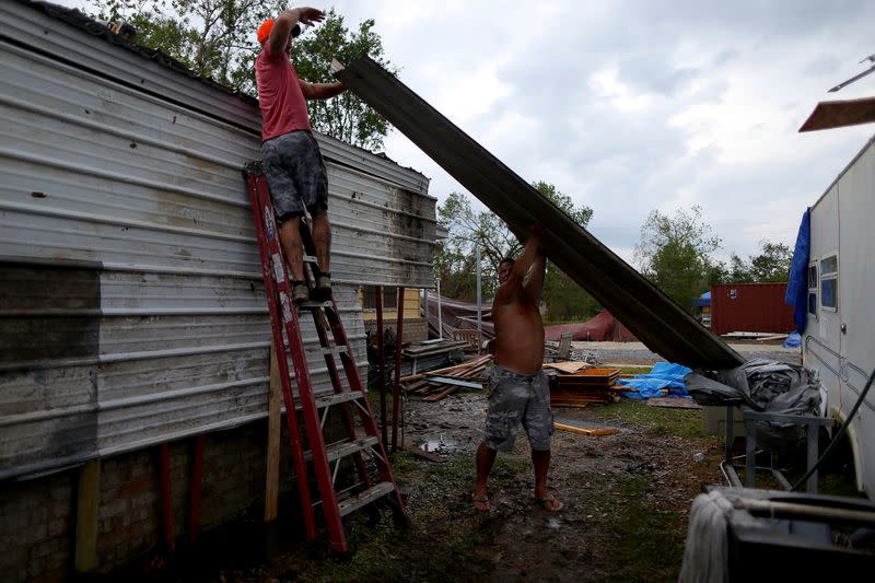 Jeremy Wood and Danny Schwem move a piece of metal roofing while making repairs as Hurricane Delta approaches in Lake Charles