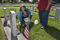 Connie Groblebe places lilacs at the grave of her in-laws, Frank and Helen Groblebe at the Mountview Cemetery on Memorial Day, in Billings, Mont., Monday, May 25, 2020. Groblebe says that with the annual Memorial Day ceremony at the cemetery curtailed by the coronavirus, it was quiet and "that's how it should be." (AP Photo/Matthew Brown)