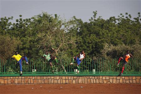 Soccer players, perched on a fence, watch a pick-up game in Niamey September 15, 2013. REUTERS/Joe Penney