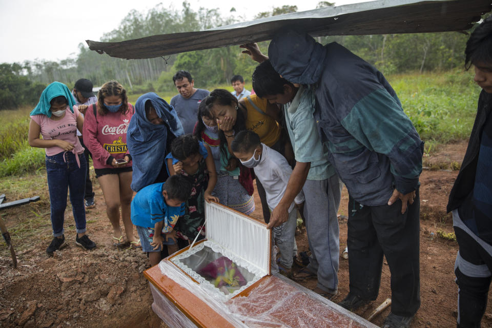 Family members look in the coffin that contains the remains of Manuela Chavez who died from symptoms related to the coronavirus at the age of 88, during a burial service in the Shipibo Indigenous community of Pucallpa, in Peru's Ucayali region, Monday, Aug. 31, 2020. The Shipibo have tried to prevent COVID-19's entrance by blocking off roads and isolating themselves. (AP Photo/Rodrigo Abd)