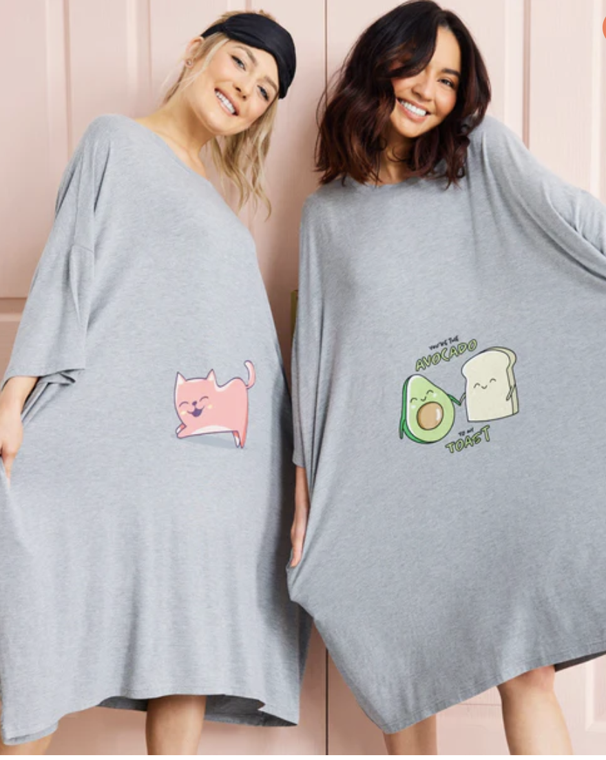 Two young woman stand smiling in their grey Oodie oversized sleep tees