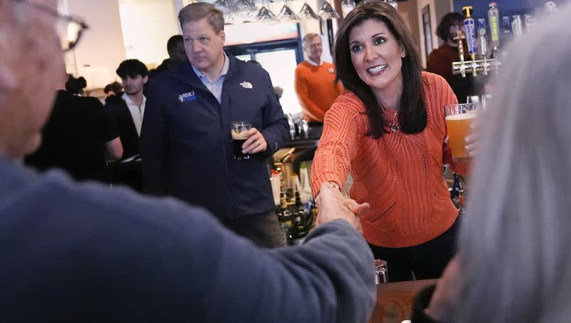 Republican presidential candidate Nikki Haley shakes hands with a patron during a campaign stop at a restaurant on Monday, Jan. 22, 2024, in Concord, N.H. At left is New Hampshire Gov. Chris Sununu.