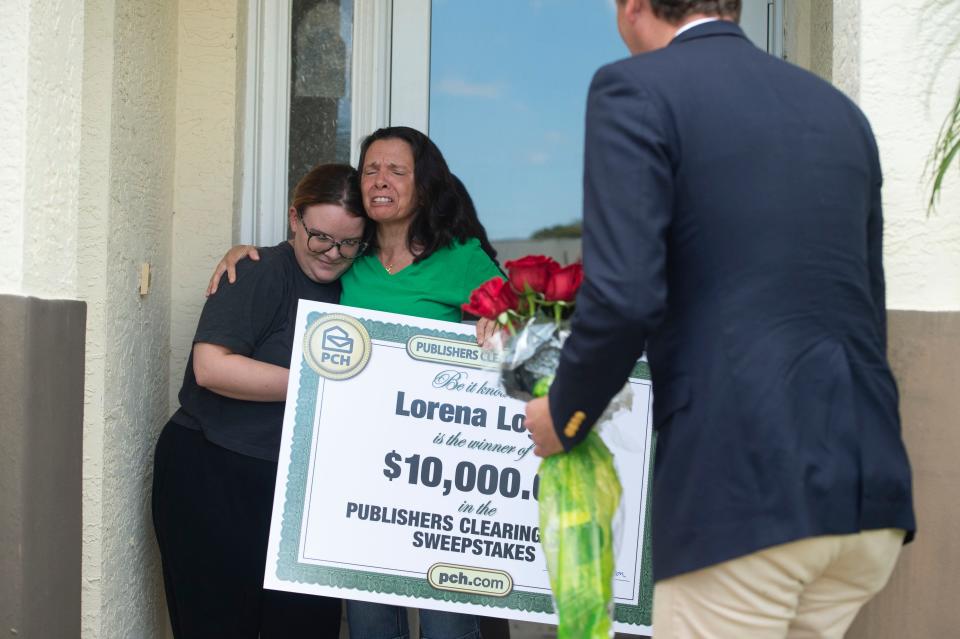“I’m taking you out to dinner,” said Publishers Clearing House sweepstakes winner Lorena Logan (center), as she embraces her daughter Ashley Logan after being presented with a $10,000 check by Howie Guja of the Prize Patrol Elite Team on Thursday, March 17, 2022, at the Logan home in Port St. Lucie. Lorena Logan has entered the sweepstakes every day for at least 30 days, Guja said. “Don’t stop playing. It’s real. Keep playing and playing and playing,” Lorena Logan said.