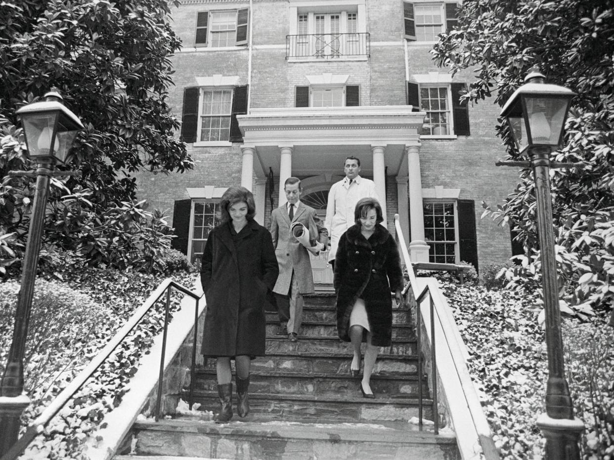 Jackie Kennedy and sister Lee Radziwill walk down front steps of Georgetown home.