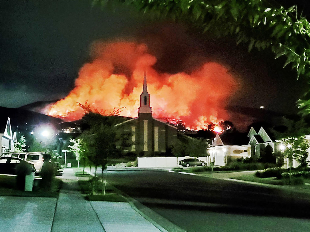 The Traverse fire burns behind homes in Lehi, Utah, early Sunday morning. Officials say fireworks caused the wildfire and forced evacuations. (Photo: ASSOCIATED PRESS)