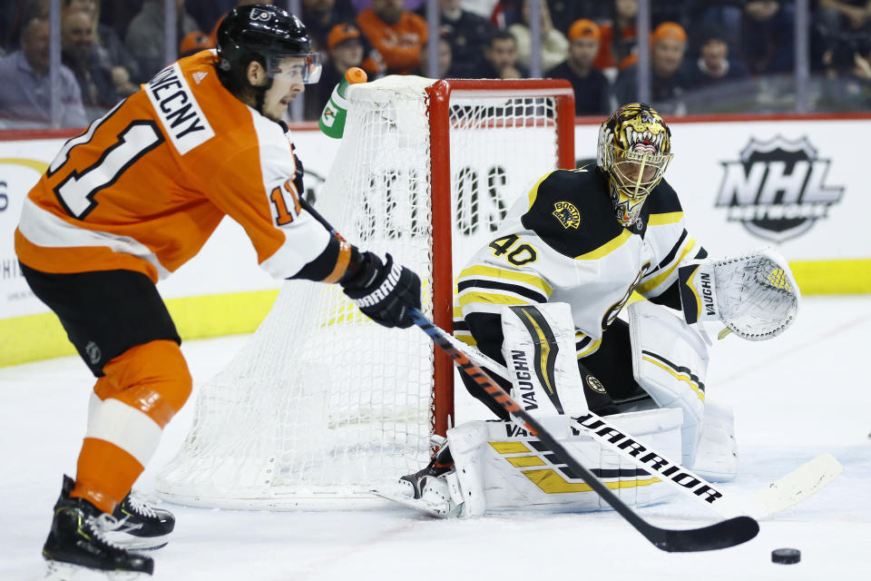 Philadelphia Flyers' Travis Konecny, left, passes the puck against Boston Bruins' Tuukka Rask during the second period of an NHL hockey game, Tuesday, March 10, 2020, in Philadelphia. (AP Photo/Matt Slocum)