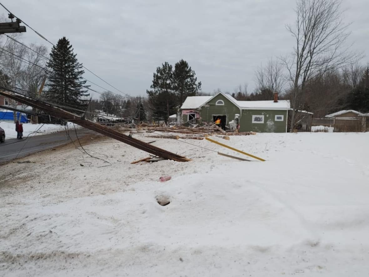 Power lines were knocked down and logs were strewn across the road when a log truck crashed into a home in Chipman on Friday afternoon. (Courtney Boyd/Facebook - image credit)