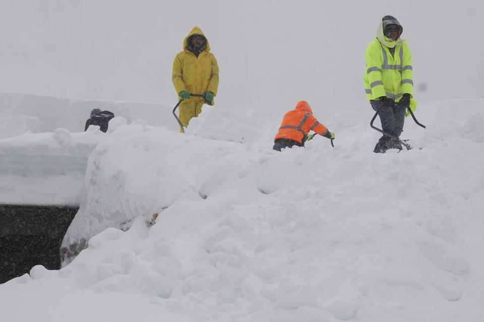 Workers clear snow off a roof of a building during a blizzard Sunday, March 3, 2024, in Olympic Valley, Calif. (AP Photo/Brooke Hess-Homeier)