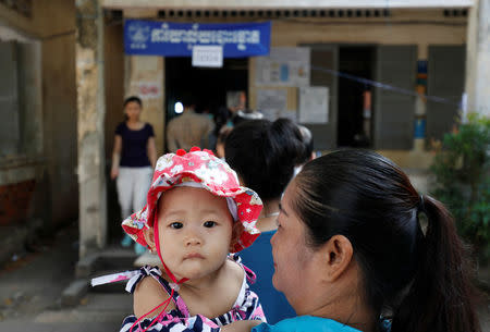 A woman holds her baby as she lines up to vote at a polling station during a general election in Phnom Penh, Cambodia July 29, 2018. REUTERS/Darren Whiteside