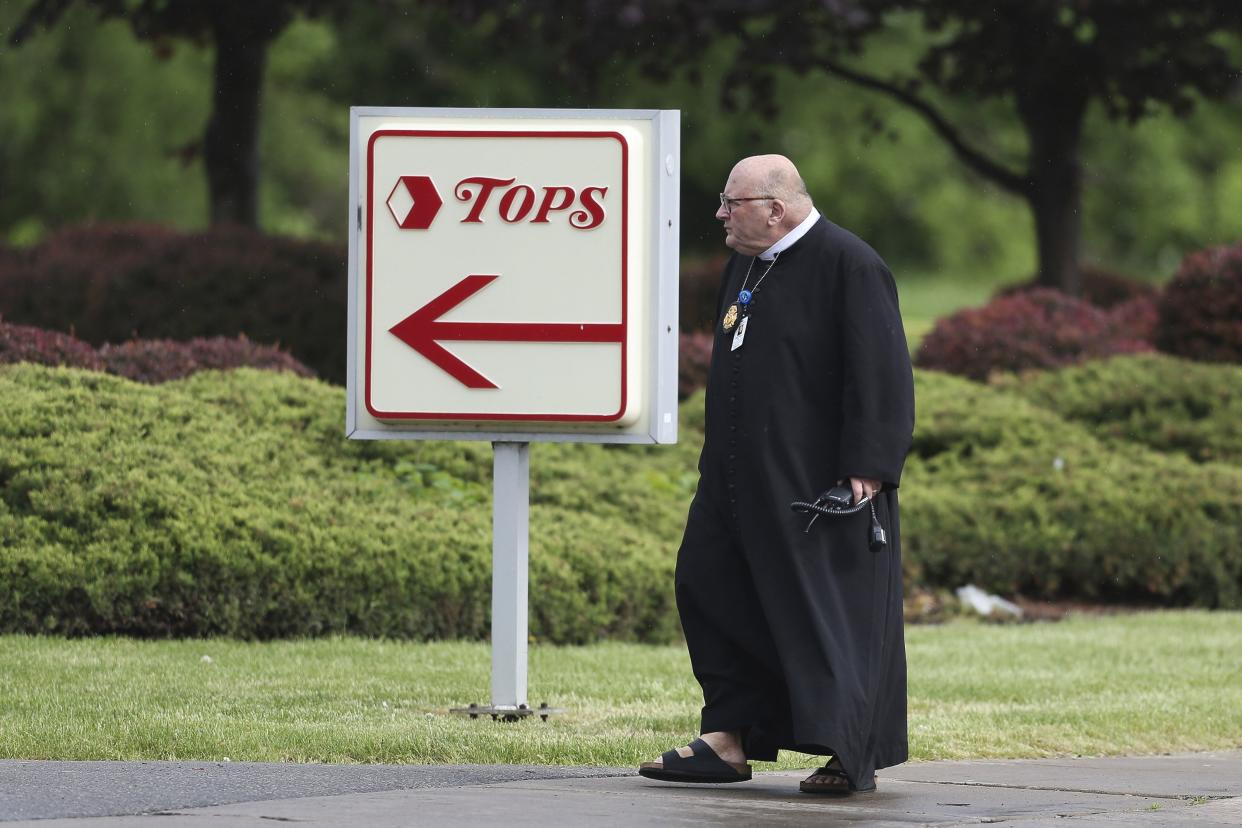 A chaplain with the Buffalo Police Department walks in the parking lot after a shooting at a supermarket, Saturday, May 14, 2022, in Buffalo, N.Y.