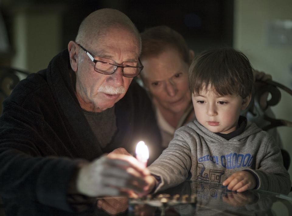 <span class="caption">Three generations light a Hanukkah candle. Holiday lights can evoke happy memories of celebrations past.</span> <span class="attribution"><a class="link " href="https://www.shutterstock.com/image-photo/jewish-family-lighting-hanukkah-candles-menorah-530079643" rel="nofollow noopener" target="_blank" data-ylk="slk:Tercer Ojo Photography/Shutterstock;elm:context_link;itc:0;sec:content-canvas">Tercer Ojo Photography/Shutterstock</a></span>