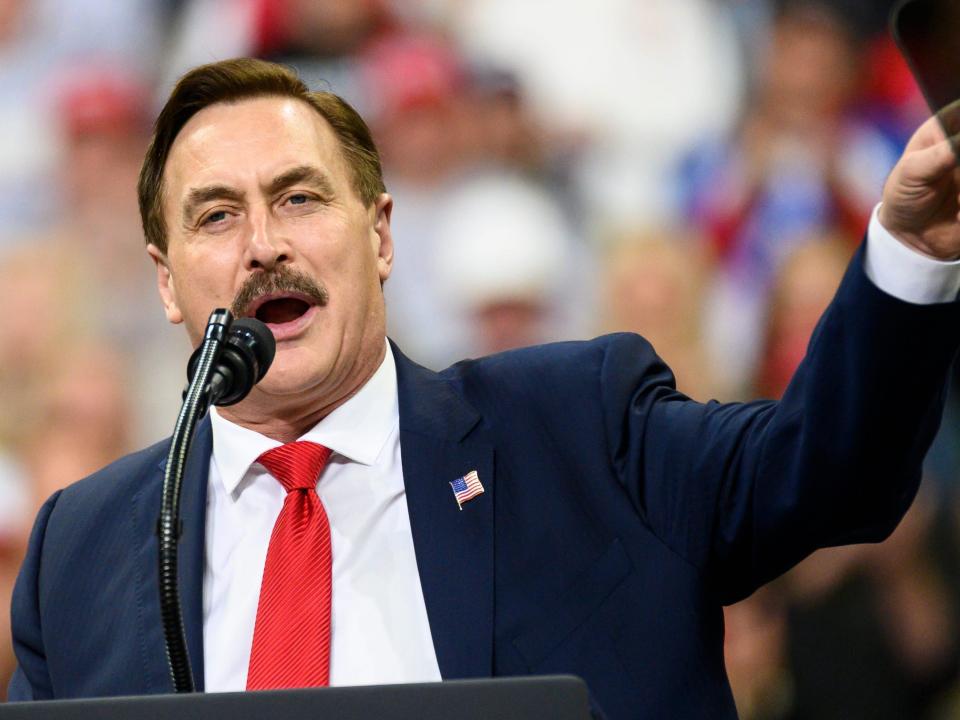 Mike Lindell delivers a speech to a crowd from behind a podium.