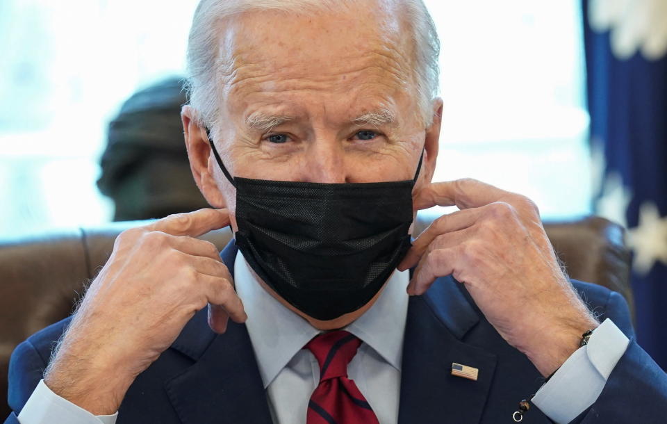 U.S. President Joe Biden takes off his mask to sign executive orders strengthening access to affordable healthcare at the White House in Washington, U.S., January 28, 2021. REUTERS/Kevin Lamarque