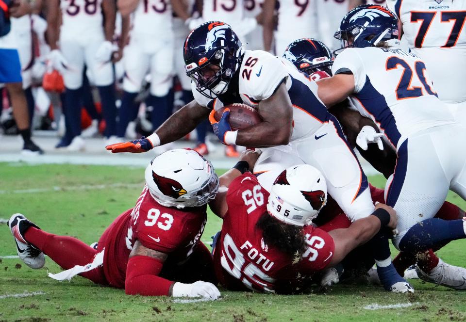 Denver Broncos running back Samaje Perine (25) is tackles by Arizona Cardinals defensive tackle Leki Fotu (95) during a preseason game at State Farm Stadium in Glendale on Aug. 11, 2023